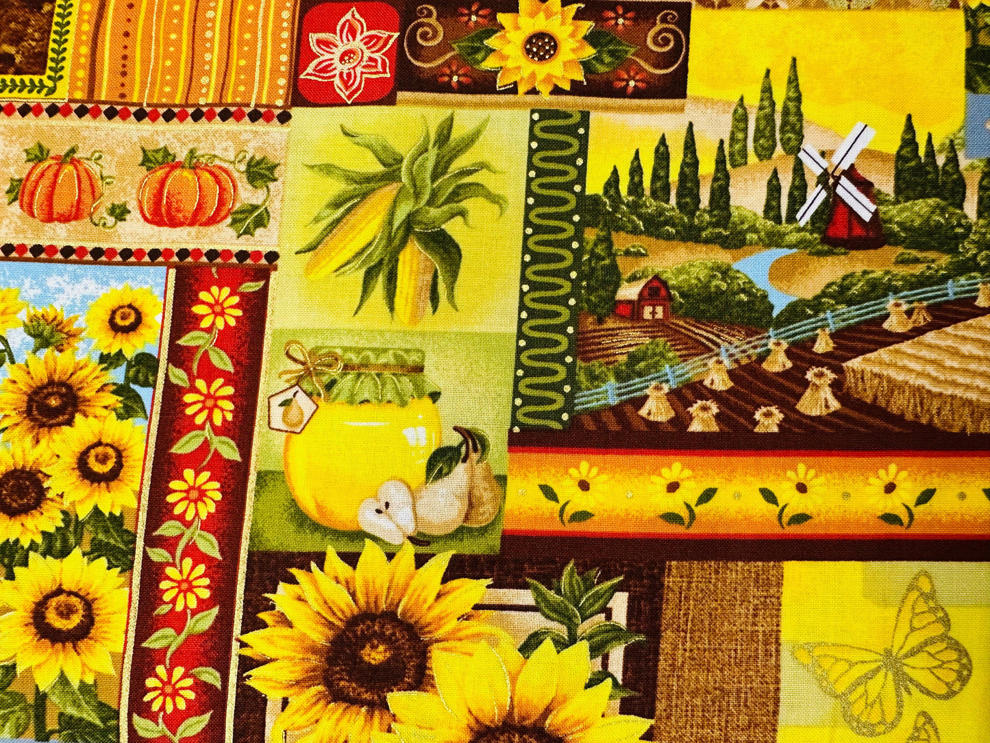 The Golden Harvest Fall Outfit by Square Up Fashions showcases vibrant patchwork fabric with sunflowers, pumpkins, a butterfly, windmill scenes, garlic, and jars in lively yellow, green, and red tones—perfect for autumn.