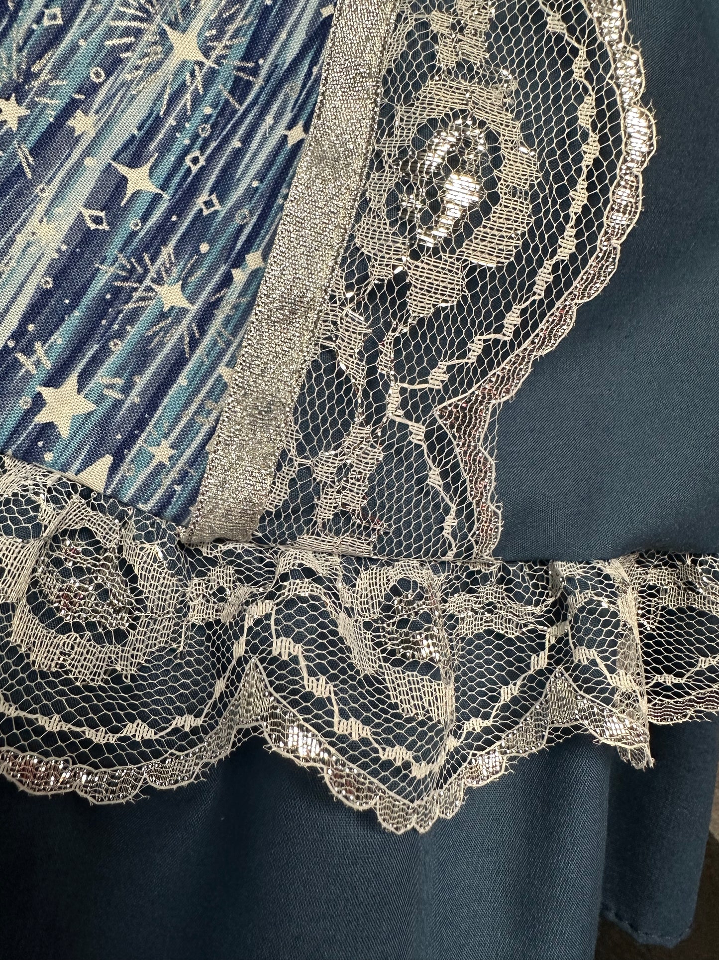 Close-up of the Starry Night Fancy Outfit by Square Up Fashions, showing sapphire blue star-patterned fabric, metallic lace trim, and a dark background.