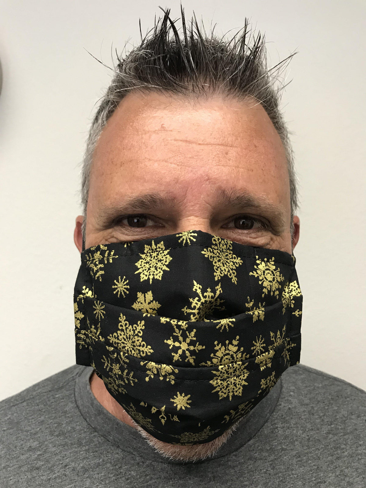 A man wearing a Square Up Fashions gold snowflake face mask with adjustable nose wire for 2 layers of protection.