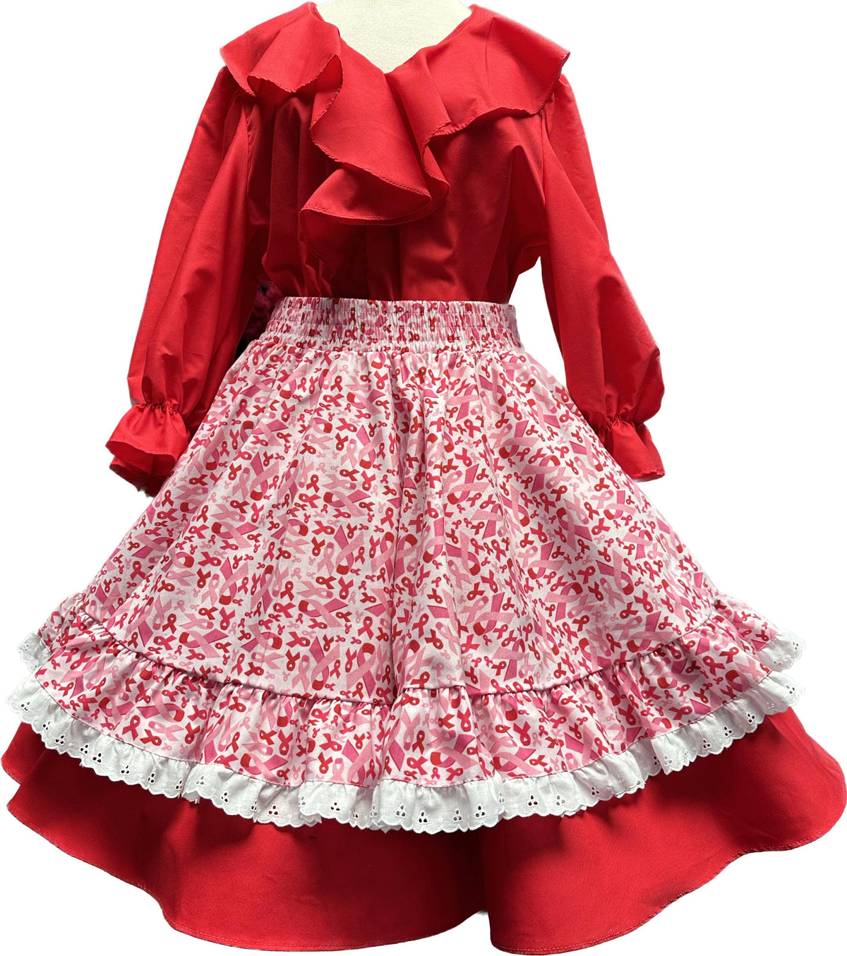 A red and white children&#39;s Pink Ribbon Apron with ruffles and Square Up Fashions ribbons.