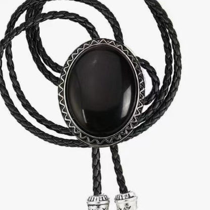 The Western Express Black Stone Bolo Tie features a large oval black centerpiece and braided leather cords with silver tips—a bold cowboy jewelry piece and classic western accessory.