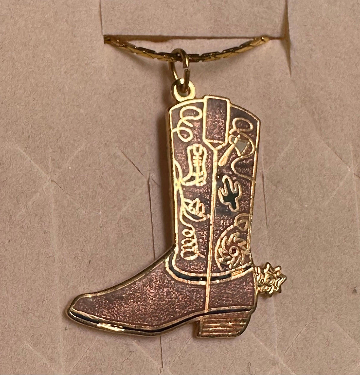 A gold Square Up Fashions Western Boot Necklace charm pendant in a jewelry box.