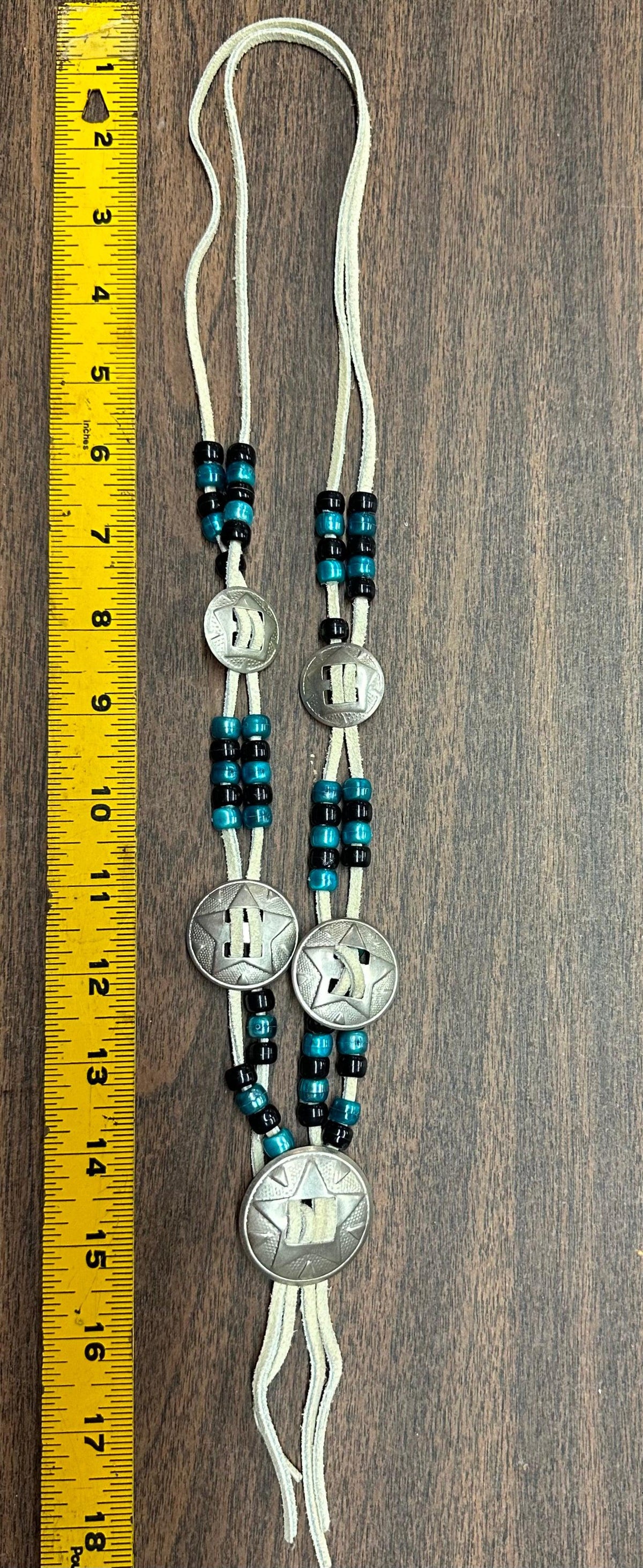 A matching set of a Concho Necklace and earrings by Square Up Fashions with turquoise beads next to a ruler.