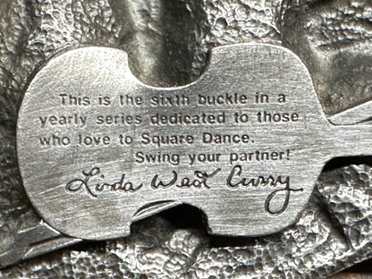 A close-up of the Square Up Fashions "Square Dance Buckle w/caller" shows: "Sixth buckle in a yearly series dedicated to those who love to Square Dance. Swing your partner! Linda Weld Curry." A 1989 commemorative item.