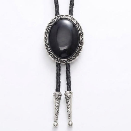 A black bolo tie necklace featuring a large oval black onyx cabochon stone surrounded by a silver-toned geometric bezel, with braided black cords and silver-toned decorative tip connectors.