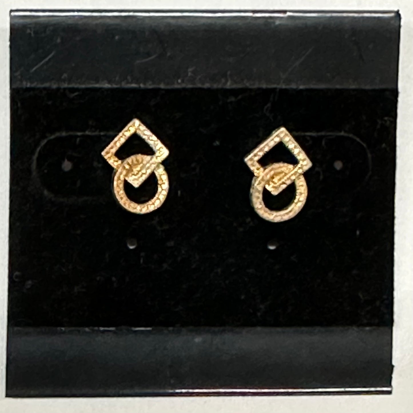 Square Up Fashions' Post Square and Round Dance Earrings feature a geometric design with a diamond-shaped top and textured circular bottom. Displayed on a black card, they're perfect as unique dance jewelry for any occasion.