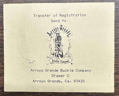 A printed card for the Square Dance Buckle w/caller by Square Up Fashions instructs to send transfer of registration to Arroyo Grande Buckle Company, Drawer C, Arroyo Grande, CA 93420. Features company logo. Made in USA.