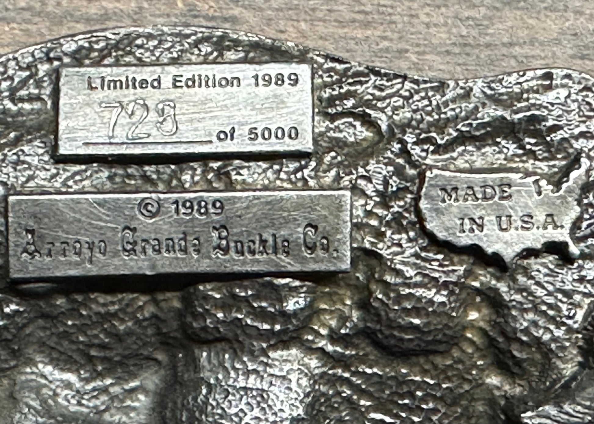 Close-up of a vintage Square Up Fashions "Square Dance Buckle w/caller," engraved with "Limited Edition 1989, 728 of 5000," "© 1989 Arroyo Grande Buckle Co.," and "MADE IN U.S.A.