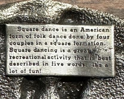 A metal plaque explains that square dance, an American folk dance of four couples in a square, is a lively, recreational activity—just as the Square Up Fashions Square Dance Buckle w/ instruments celebrates this tradition.