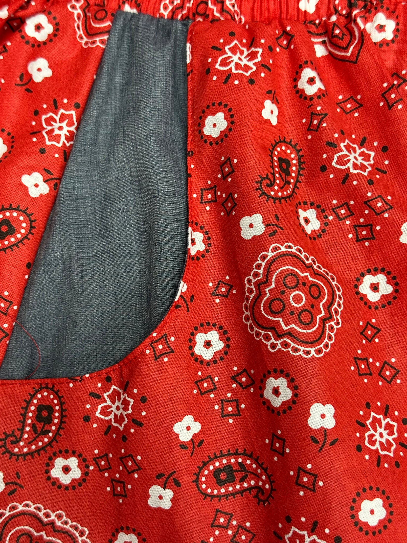 A close-up of the Country Square Dance Outfit by Square Up Fashions, featuring red bandana print fabric and a visible gray pocket lining on the left side.