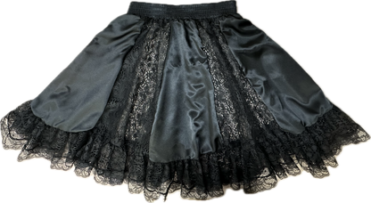 The Charmeuse Square Dance Skirt by Square Up Fashions is a black knee-length skirt featuring alternating satin and lace panels, made from luxe charmeuse fabric with a delicate lace-trimmed hem.