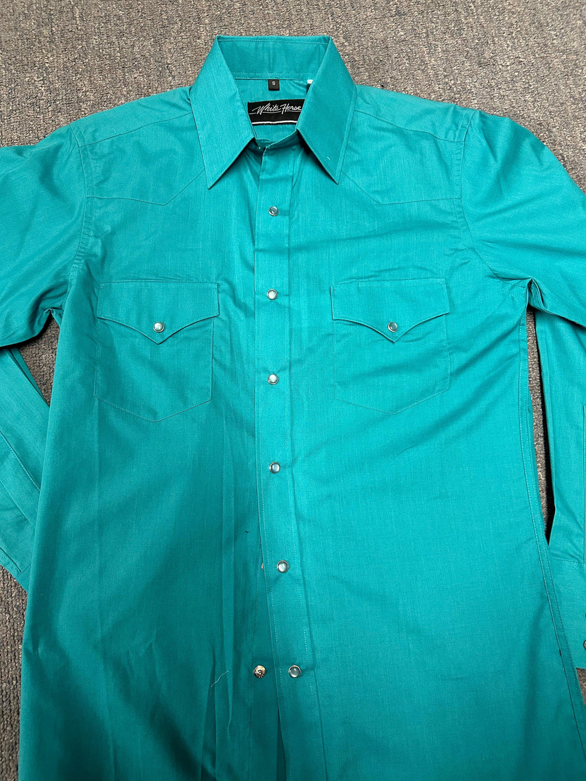 A men&#39;s WHITEHORSE brand western shirt in turquoise on the floor.
