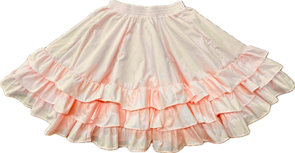 The Square Up Fashions 3 Ruffle Square Dance Skirt is a light pink skirt with three ruffle layers and an elastic waistband, shown laid flat on a white background. Custom sizes available for the perfect fit.