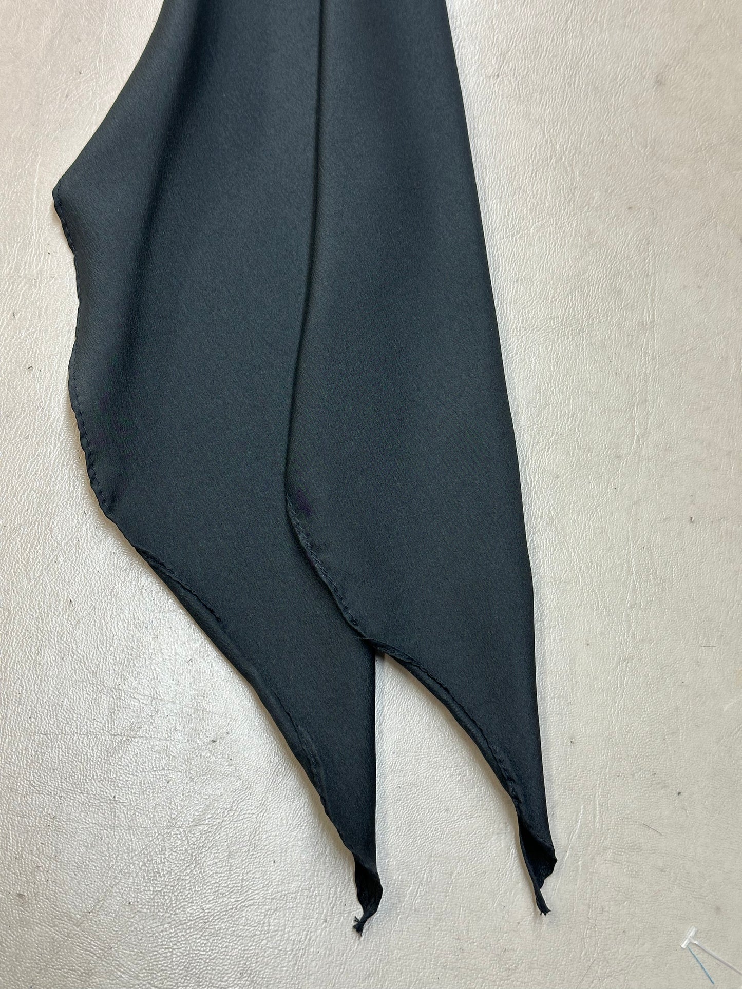 A CLEARANCE Light Weight Thin Polyester Scarf Tie by Square Up Fashions, in solid black with two pointed ends, rests on a light textured surface.