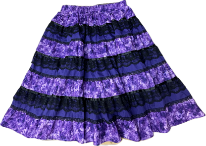 The Tone on Tone Prairie Skirt by Square Up Fashions features alternating bands of purple tie-dye and black lace, making this standout black lace skirt a stylish addition to any women's wardrobe.