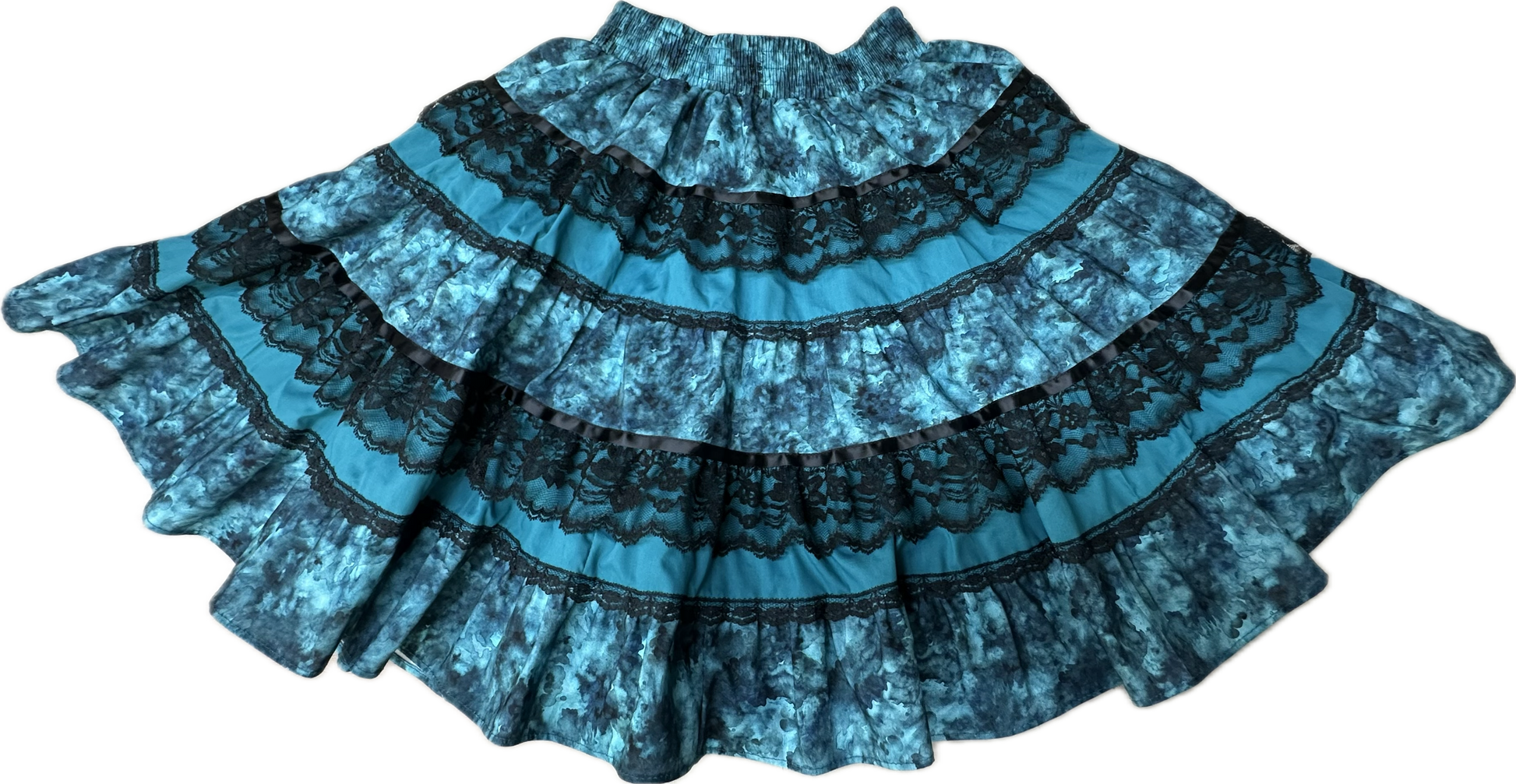 The Tone on Tone Square Dance Skirt by Square Up Fashions, featuring blue and black tiers with black lace detailing, is displayed spread out flat on a white background.