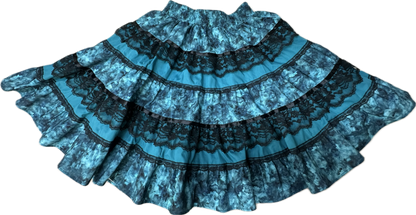 The Tone on Tone Square Dance Skirt by Square Up Fashions, featuring blue and black tiers with black lace detailing, is displayed spread out flat on a white background.