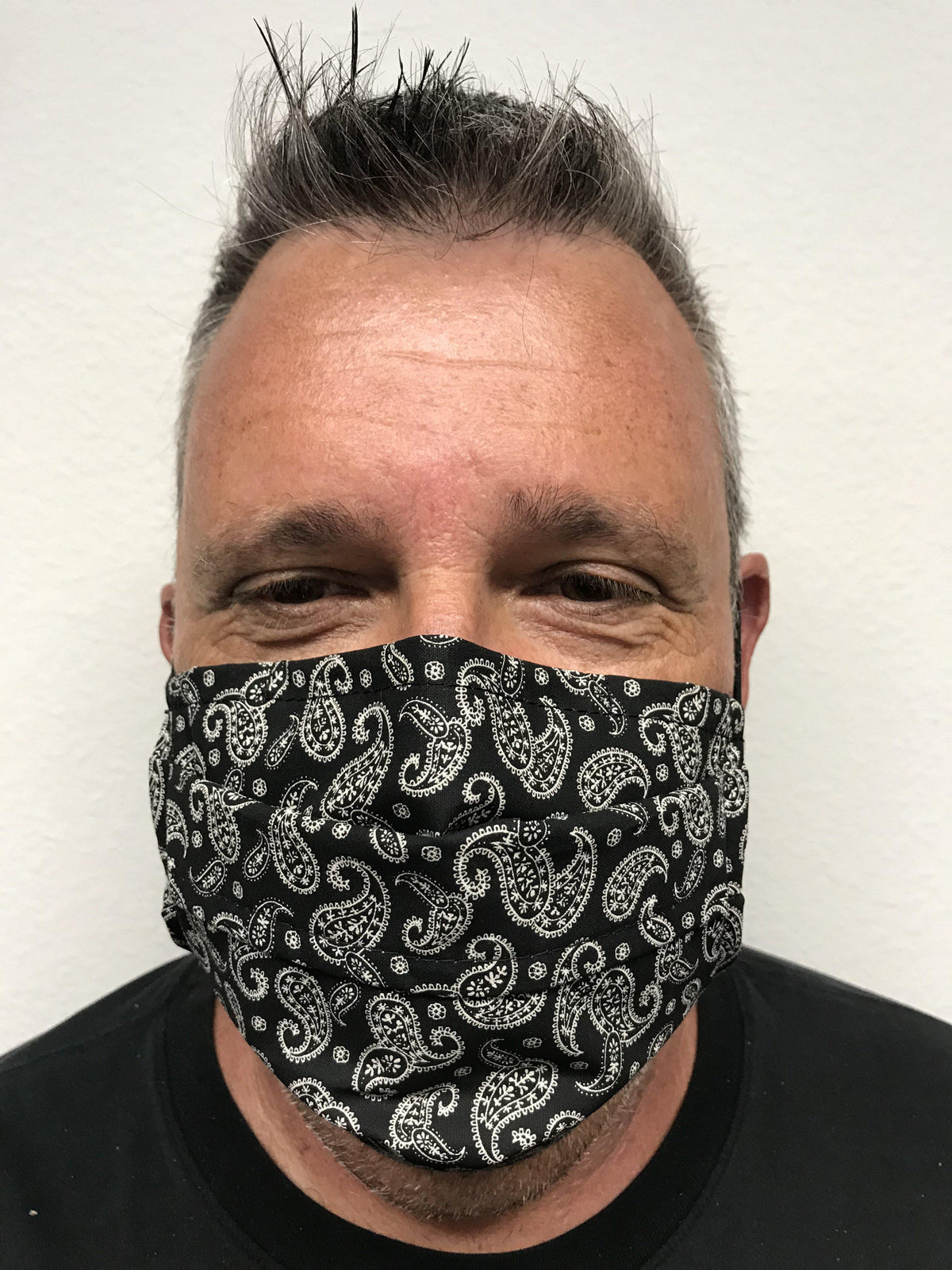 A man wearing a black paisley Square Up Fashions face mask with adjustable nose wire.
