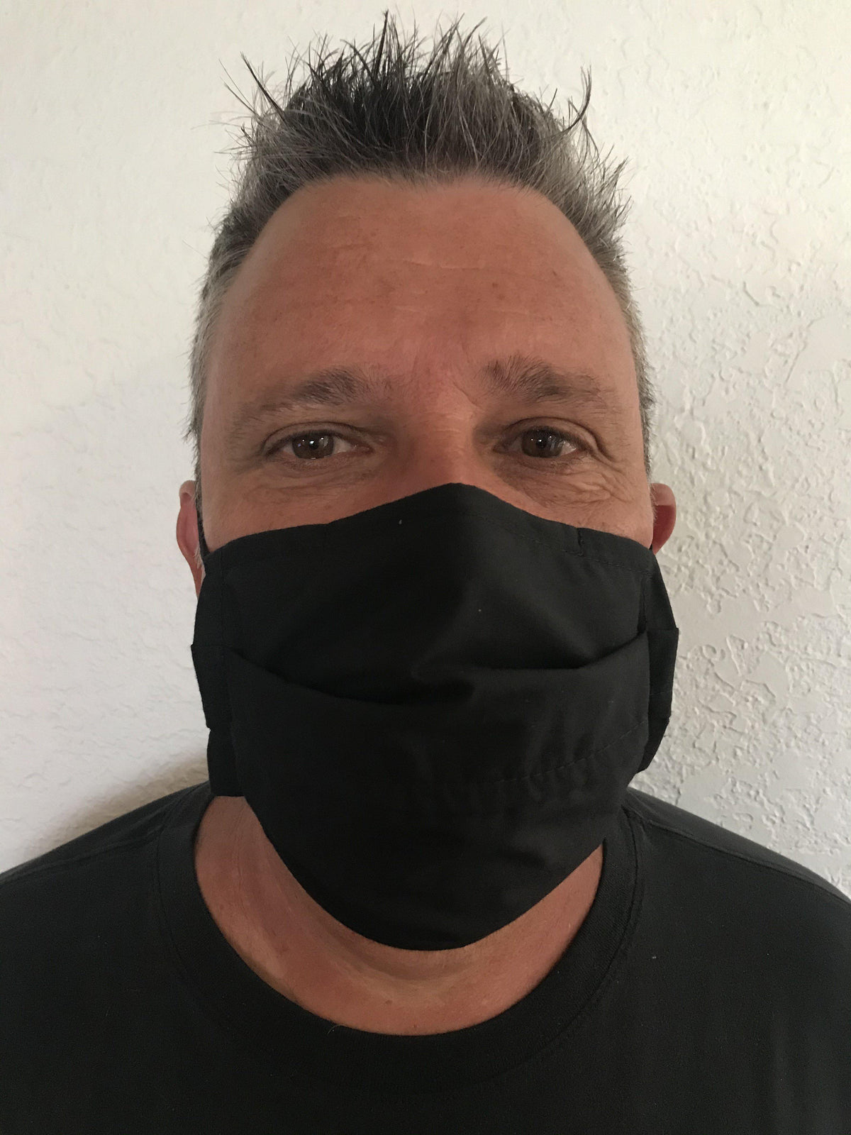 A man wearing a Square Up Fashions washable and reusable black face mask with an adjustable nose wire, providing 2 layers of protection.