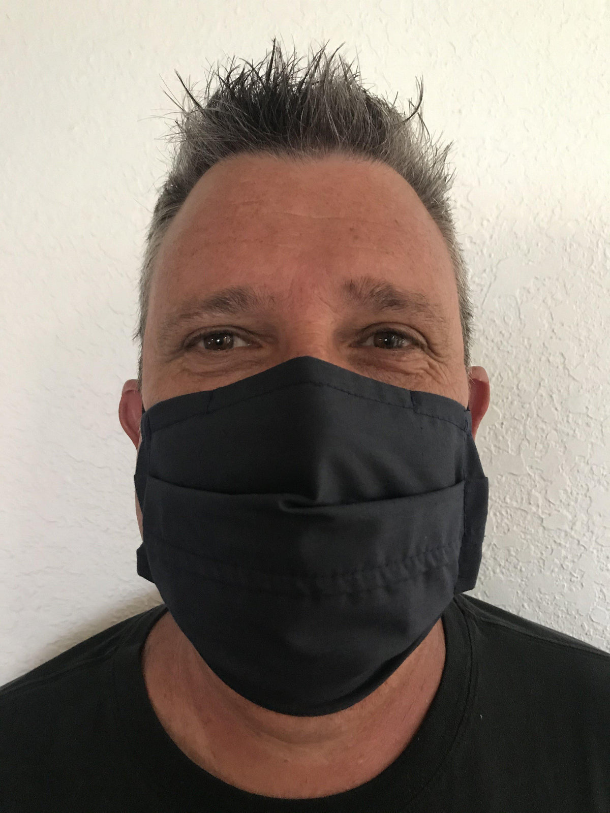 A man wearing a Square Up Fashions washable and reusable black face mask with an adjustable nose wire and offering 2 layers of protection.