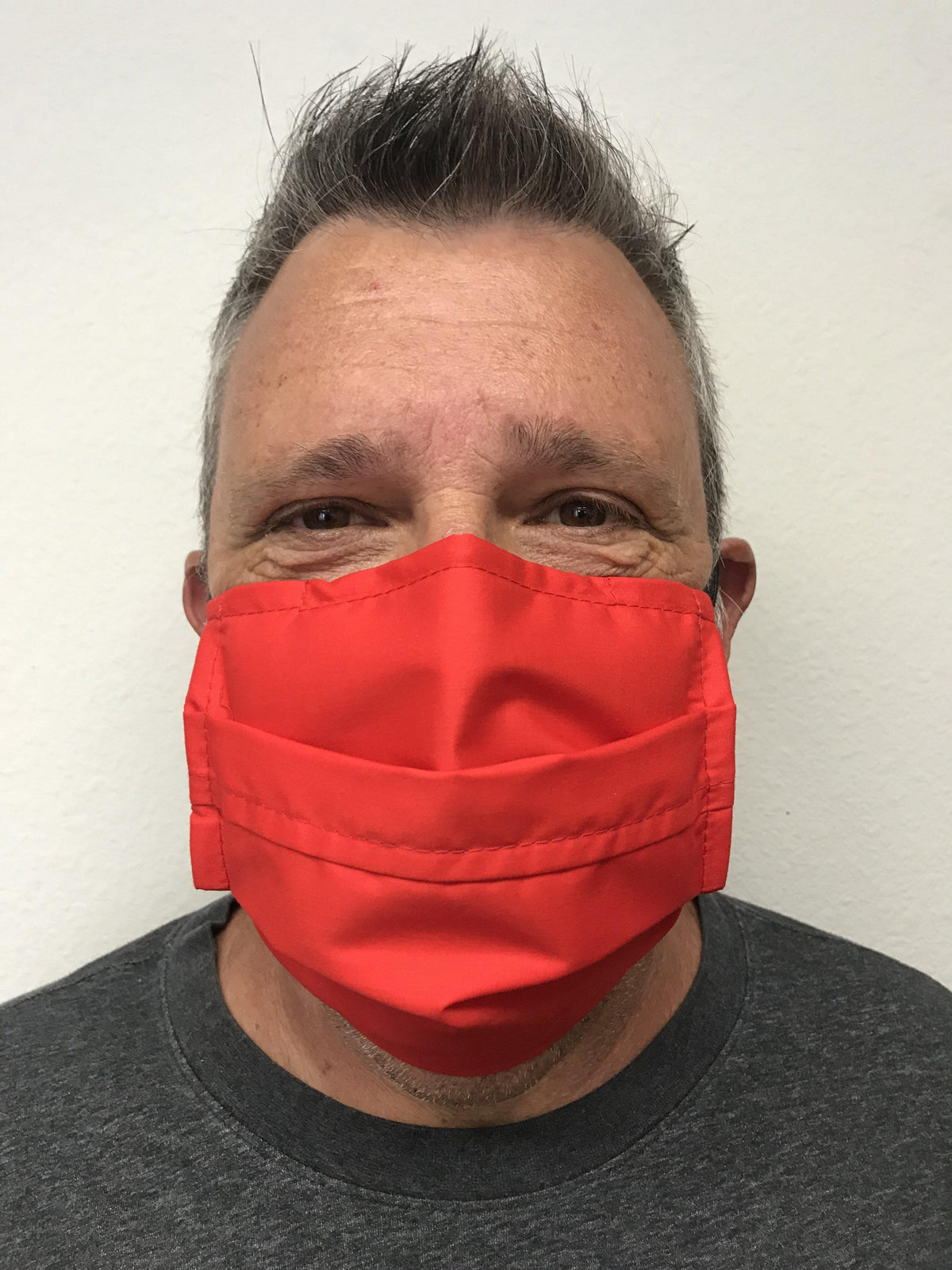A man wearing a Square Up Fashions washable and reusable red face mask with an adjustable nose wire for added comfort and 2 layers of protection.